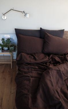 a bed with dark brown sheets and pillows