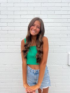 a woman standing in front of a white brick wall with her hands on her hips