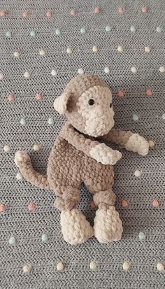 a crocheted monkey sitting on top of a bed next to polka dot sheets