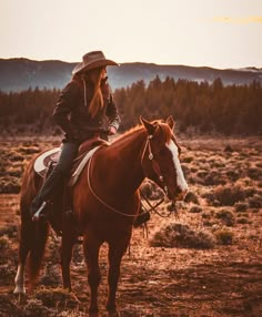 a woman riding on the back of a brown and white horse in an open field