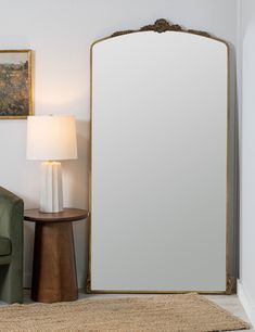 a large mirror sitting next to a green chair in a living room on top of a rug