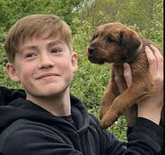 a young boy holding a puppy in his hands