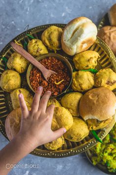 a person reaching for some food on a platter with bread and other foods in it