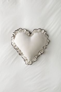 a white heart shaped pillow sitting on top of a bed