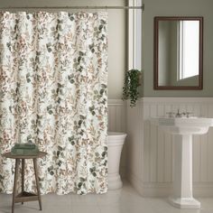 a bathroom with a sink, toilet and shower curtain that has floral print on it