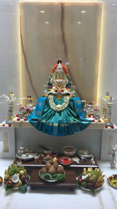 there is a statue in the middle of a table filled with fruits and other items