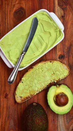 avocado spread in a bowl next to an avocado and bread