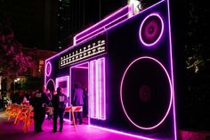 people are standing in front of a building that is lit up with purple lights and speakers