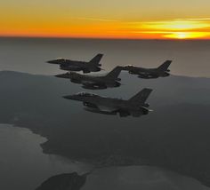 four fighter jets flying in formation at sunset