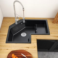 a black kitchen sink sitting on top of a wooden counter next to a cutting board