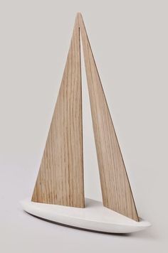 a small wooden sailboat sitting on top of a white plate with a wood base