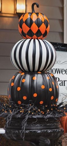 three pumpkins stacked on top of each other in front of a halloween party sign