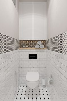 a white bathroom with black and white tiles on the walls, toilet and cabinets in the corner