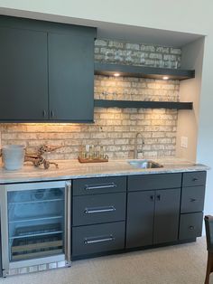 a kitchen with grey cabinets and white marble counter tops, built in wine coolers