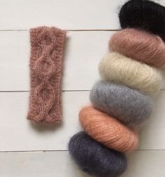 several skeins of yarn are laid out on a white wooden surface next to each other