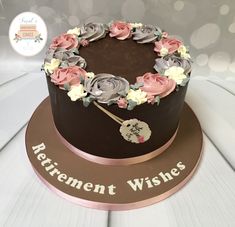 a chocolate cake with pink and white flowers on top is sitting on a plaque that says retirement wishes