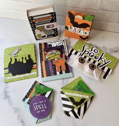 several halloween cards and envelopes on a white counter top with black and green accents