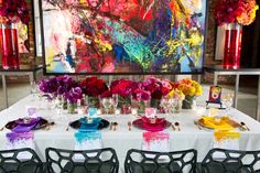 the table is set up with colorful flowers and place settings for guests to sit at