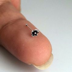 a finger with a tiny black flower on it's tip and a white background