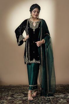 Black silk velvet kurta with bell sleeves, hand embroidery in zardozi, aari, stone and mirror work. Paired with satin silk bottle green pants with embroidered border and bottle green organza dupatta.
Component: 3
Pattern: Embroidered
Type Of Work: Zardozi, Aari, Stone and Mirror Work
Neckline: Cut work Round
Sleeve Type: Bell Sleeves
Fabric: Kurta: Silk Velvet, Lehenga: Satin Silk, Dupatta: Organza
Color: Black
Other Details: 
Side slits on kurta
Embroidered dupatta
Closure:
Pants: Side zip
Occa V Neck Kurta, Velvet Kurta, Eid Dress, Velvet Lehenga, Velvet Dress Designs, Embroidered Border, Embroidered Dupatta, Sharara Set, Organza Dupatta