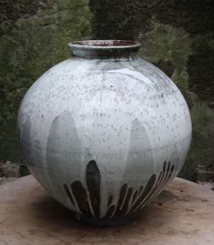 a white and black vase sitting on top of a wooden table next to a wall