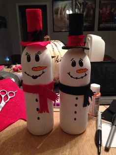 two snowmen made out of plastic bottles sitting on a table