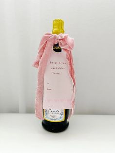 a bottle of wine with a pink bow on it's neck and label that says because you can't drink flowers