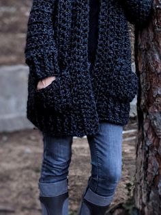 a woman standing next to a tree while talking on a cell phone and wearing boots