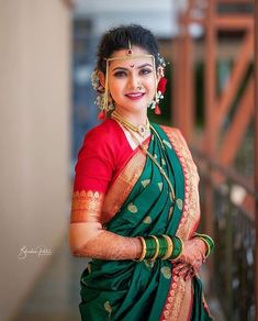 a woman in a green and red sari posing for the camera with her hands on her hips