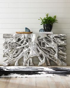 a wooden table with a plant on top of it next to a white and black rug