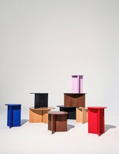 four different colored tables sitting on top of each other in front of a white wall