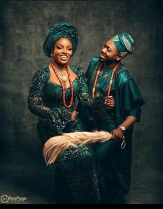 two women dressed in green and gold posing for a photo with one holding a feather