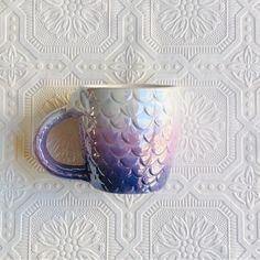 a blue and white coffee cup sitting on top of a table next to a wall