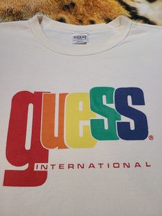 90's Guess International Shirt. Made In USA. Size tag reads One Size Fits All. Refer to measurements. Armpit to armpit is 23 inches. Top of shoulder to bottom front is 24 inches. A little boxy..maybe a crop top. Pre-owned condition. Color is a white. Not as white as it once was. A small feint spot on the front bottom. And the collar shows signs of wear with some staining/yellowing. An oxy bath would help remove the stains. Overall has a nice worn faded vintage look. Refer to pictures and message Ski Shirts, 90s Tees, Bird Shirt, Mountain Shirt, Graphic Tshirt Design, Front Bottoms, Fashion Graphic