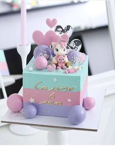 a cake decorated with pink, blue and purple decorations on top of a white table