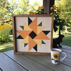 a coffee cup sitting on top of a wooden table next to a framed piece of art