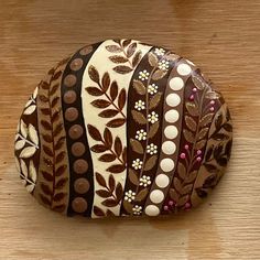 a decorative rock sitting on top of a wooden table covered in lots of brown and white designs