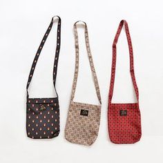 three small purses are lined up on a white surface, one has a strap and the other has a cross - body bag