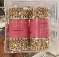 the pink bracelets are stacked on top of each other in a clear box with gold trim