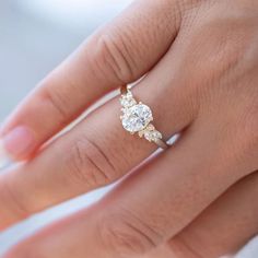 a woman's hand with a diamond ring on top of her finger and an engagement band