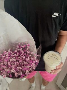 a man holding a bouquet of pink flowers and a cup of coffee