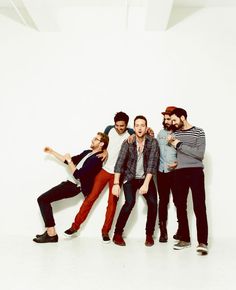 five young men are posing together in front of a white wall and one is pointing at the camera