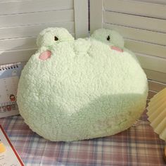 a white stuffed animal sitting on top of a table next to a book and fan