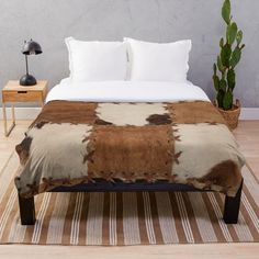 a brown and white cowhide pattern on a bed with pillows, blanket and lamp