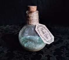 a bottle filled with blue liquid sitting on top of a lace covered table cloth next to a tag