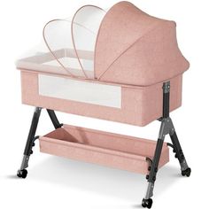 a pink baby crib with wheels and storage bins on the bottom, in front of a white background