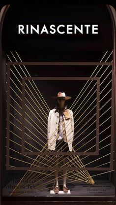 a man wearing a hat and coat standing in front of a display with the words rinascente on it