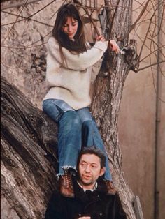 two people sitting on top of a tree