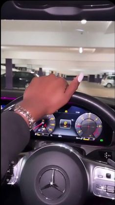 a hand on the steering wheel of a car with an electronic display in front of it