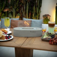 an outdoor table with food and drinks on it